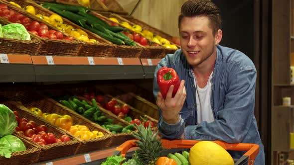 Man Examines Bell Pepper at the Supermarket