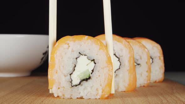 Human Hand Takes A Sushi From A Row By Chopsticks