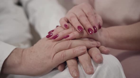 Close-up of Female Caucasian Mature Hands Touching Husband's Palms. Senior Married Retirees