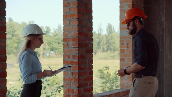 Two Architects Working On Building Model Blueprints. Engineers In Safety Helmet Construction House.