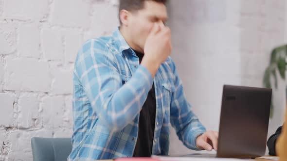 Young Handsome Caucasian Man Sneezing Sitting in Cafe with Laptop on Table