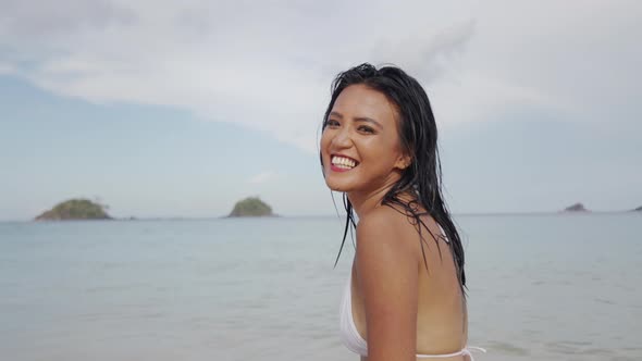 Woman Laughing To Camera In Bikini On Beach