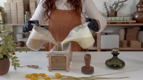 Woman pouring liquid soap into mold in artisan manufacture