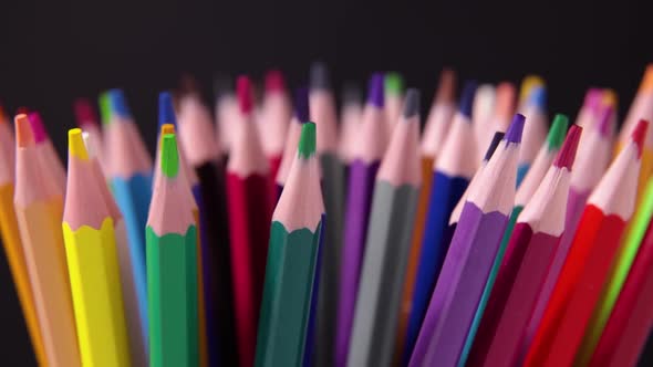 Cool coloured pencils set rotates slowly on the black background close-up shot