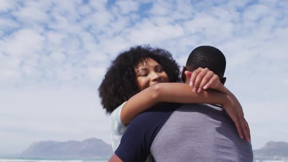 African american couple embracing and smiling at the beach