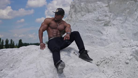 Handsome athlete man showing muscles on the rocky mountain