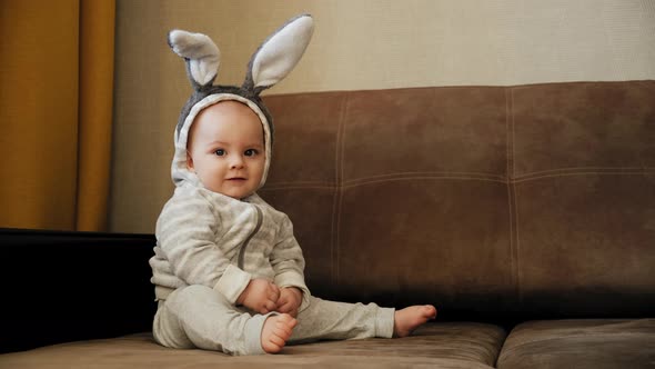 Funny Baby with Bunny Ears Sitting on Sofa Easter Concept