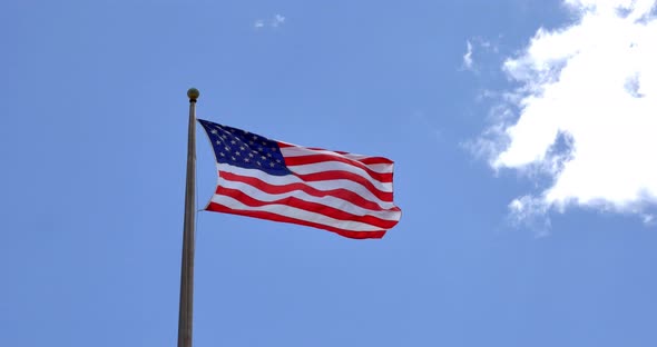 4K American flag - star and stripes floating over a cloudy blue sky