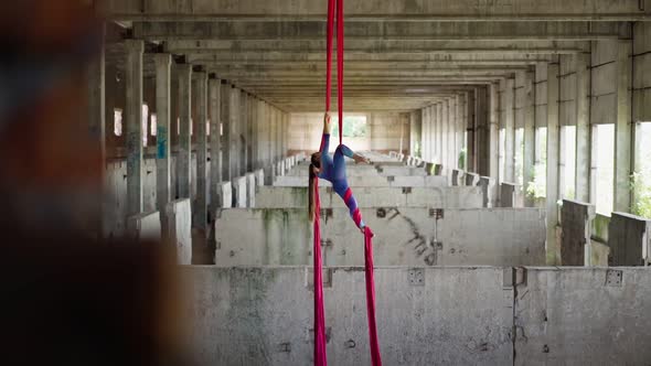 Athletic graceful woman aerialist with a steep stretch in sports overalls does a acrobatic trick