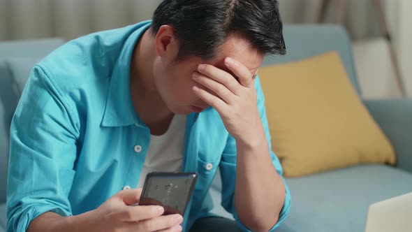 Asian Man With A Laptop Holding Credit Card And Smartphone Shaking His Head Due To Unable Pay Money