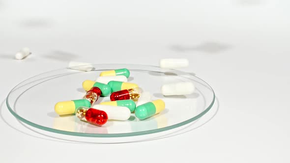 Closeup of Different Medical Pills Falling on Petri Dish on White Background