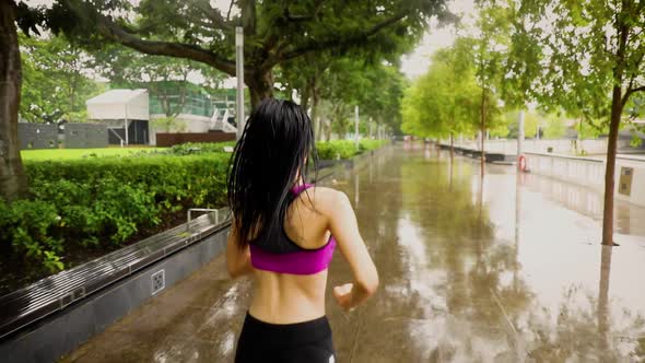 Middle-aged Asian woman jogging in the rain in Singapore 