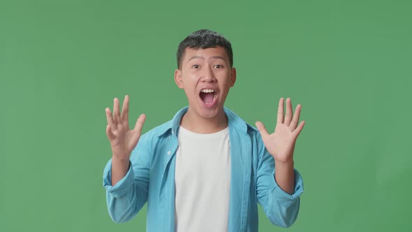 The Shocked Young Asian Boy Grabbing Her Head While Saying Wow On Green Screen Background