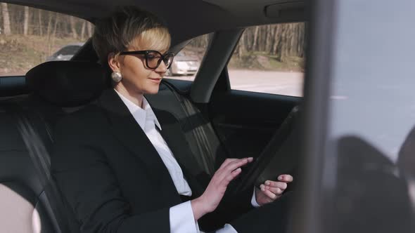 A Businesswoman in Glasses Is Working in a Car