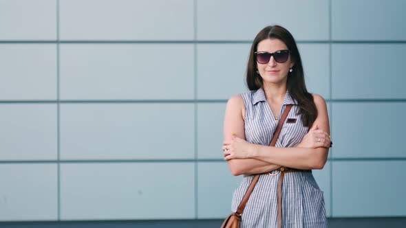 Handsome Young Woman in Sunglasses Standing with Arms Crossed