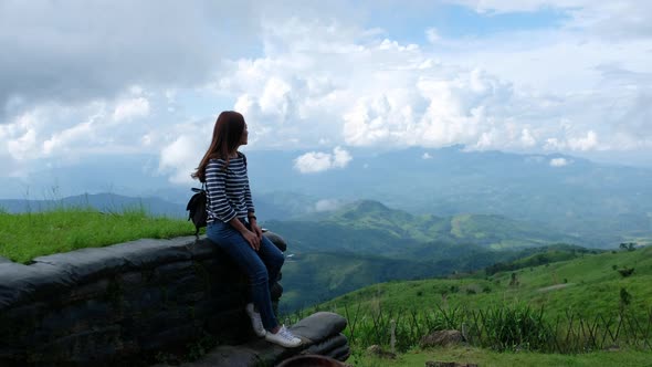 A female traveler sitting and looking at a beautiful mountain and nature view