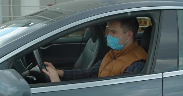 Man in Car with Surgical Mask on Face Against Coronavirus Disease 2019. COVID-19 Pandemic