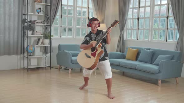 Asian Boy Playing Guitar, Sing A Song And Dancing At Living Room