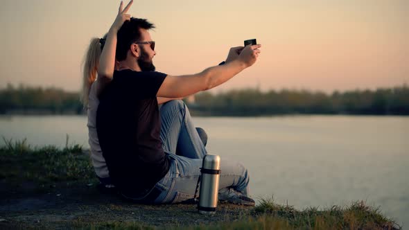 Couple Taking Selfie On Mobile Phone At Sunset.Silhouette Couple In Love Taking Selfie On Smartphone