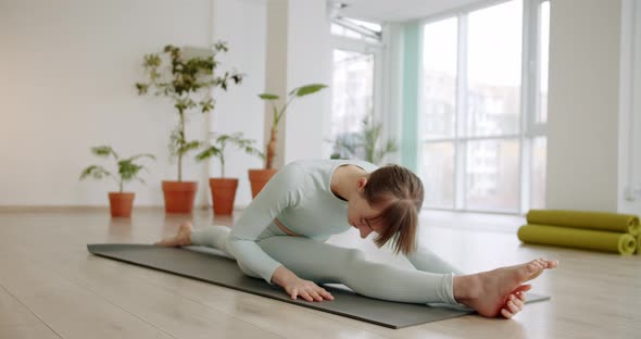 A Beautiful Woman Practices a Spagat Exercises in Bright Studio Anjaneyasana