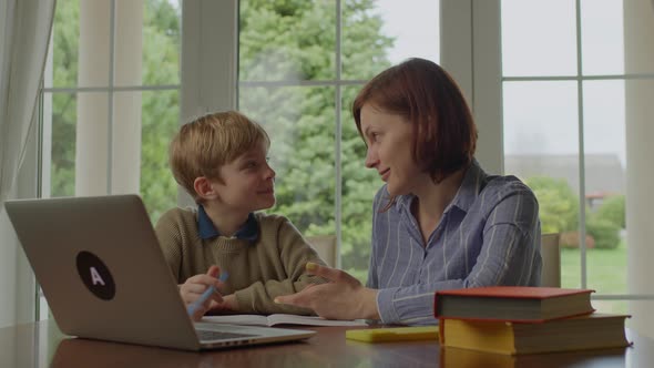 Young 30s Mother Making Online Homework with School Kid at Home