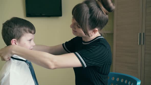 Mother Dresses a Child To School, Straightens His Clothes, Smiling.