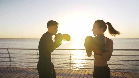 Young Woman in Sportswear is Boxing with Her Trainer