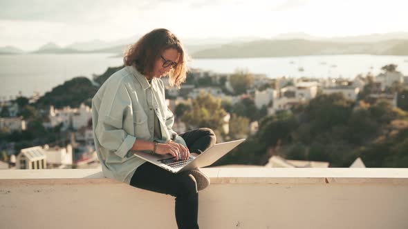 Young Woman Student Enjoying a City Top View While Using Her Laptop