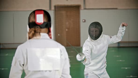 Two Young Women Fencers Having a Training in the Gym - Standing in the Welcome Poses and Starting