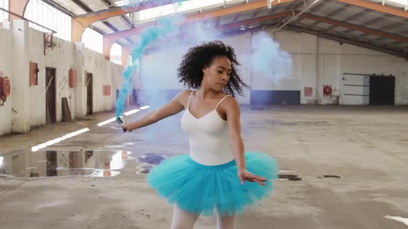 Female dancer in an empty warehouse holding smoke grenade