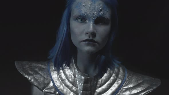 Alien with Blue Skin Stands and Looks at the Camera alt