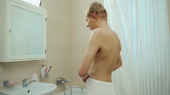 Handsome Man Looking Face In Front Of Mirror. Sexy Manat Bathroom.