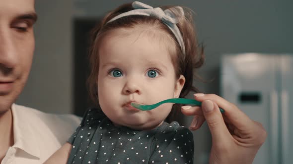 Young Parents Feed Baby Daughter at Home