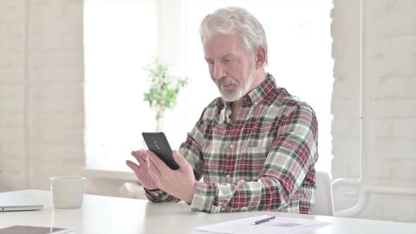 Casual Old Man Celebrating Success on Smartphone