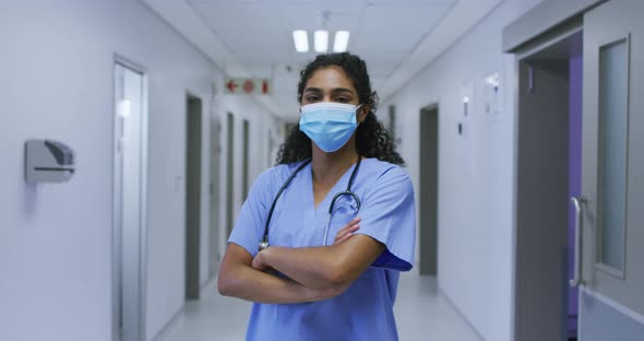Portrait of asian female doctor wearing face mask and scrubs standing in hospital corridor