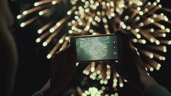 Silhouette of a Man Photographing Fireworks at Night Sky