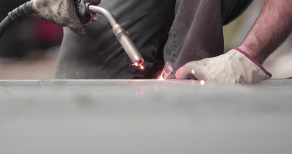 A Skilled Male Worker Wearing Gloves Holding A Welding Gun Welding The Metal Edge Then Measures Usin