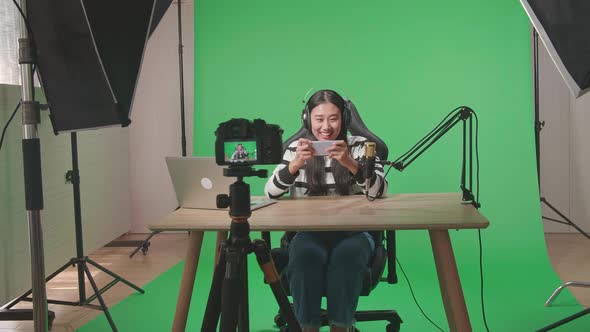 Camera Recording Woman Using Mobile Phone Playing Game On The Green Screen With Light Equipment