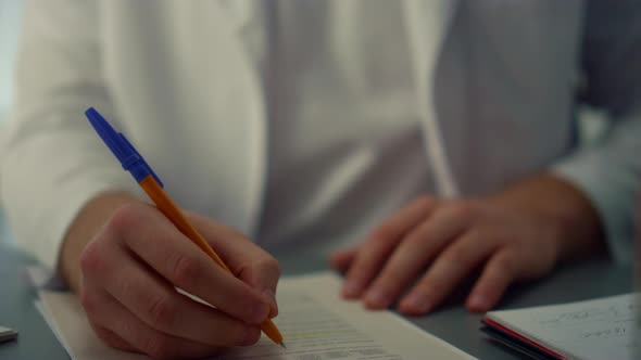 Man Surgeon Writing Notes in Medical Journal Sitting Hospital Office Close Up