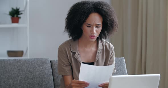 Young Foreign African Woman Sitting on Couch Checking Mail, Receiving Eviction Letter, Debt Notice