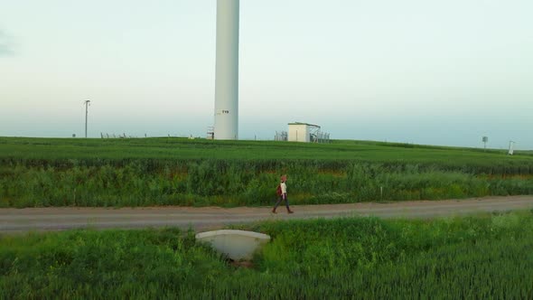 Young hiker with a backpack near an eco park with green energy windmills, aerial view