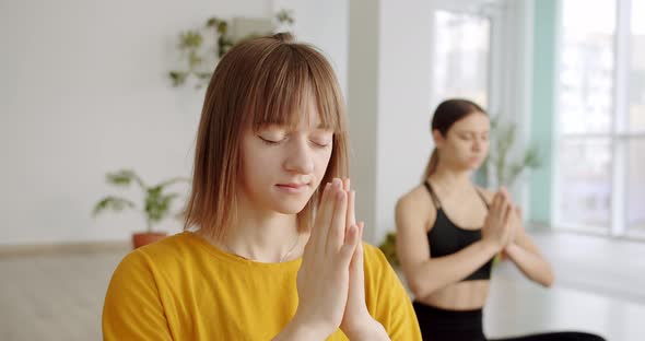 Relaxed Young Women in Sportswear is Meditating in Lotus Position Yoga Class