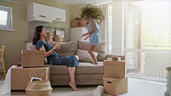 Young Mother and Her Little Daughter Jumping on Bed. Funny Pillow Fight. Play Together and Enjoy the