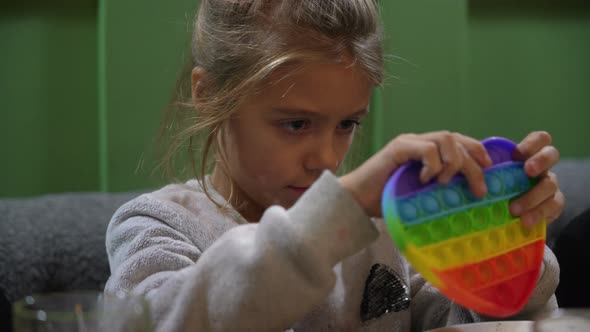 Kid Girl Play in Antistress Toy Popit at Cafe