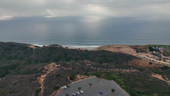 paragliders flying from launch pad above hill on the coast of La Jolla, San Diego, CA. Aerial pannin