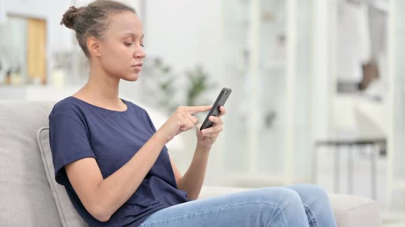 Serious African Woman Using Smartphone at Home 