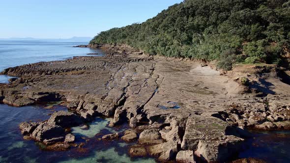 Aerial Approach Towards Chiseled And Eroded Rock Formations Of Goat Island Shore On A Bright Sunny D