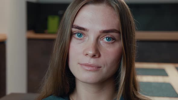 Close-up Portrait of Happy Young Woman with Beautiful Blue Eyes Looking at Camera Sit on Sofa Alone