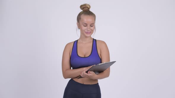 Happy Young Blonde Woman As Gym Instructor Talking and Holding Clipboard