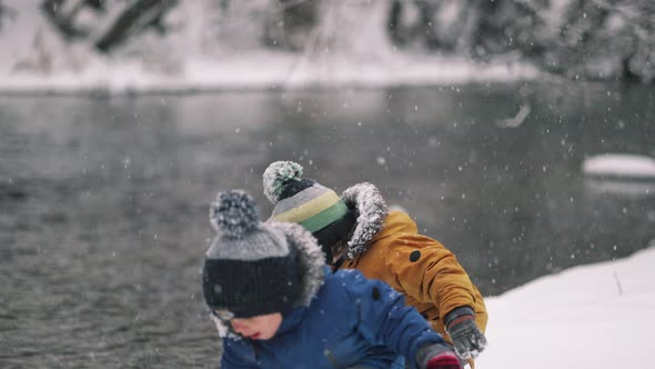 Little Twins Boys Playing with Snow Near River at Winter